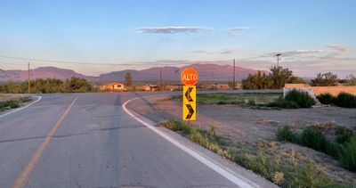 ALTO, a Mexican stop sign, is lit up by the same beautiful morning alpine glow on desert mountains in the distance.