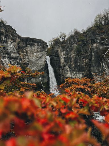 The waterfall (Chorillo del Salto) is the main focus here while the red leaves provide additional context that the photo was captured in the fall